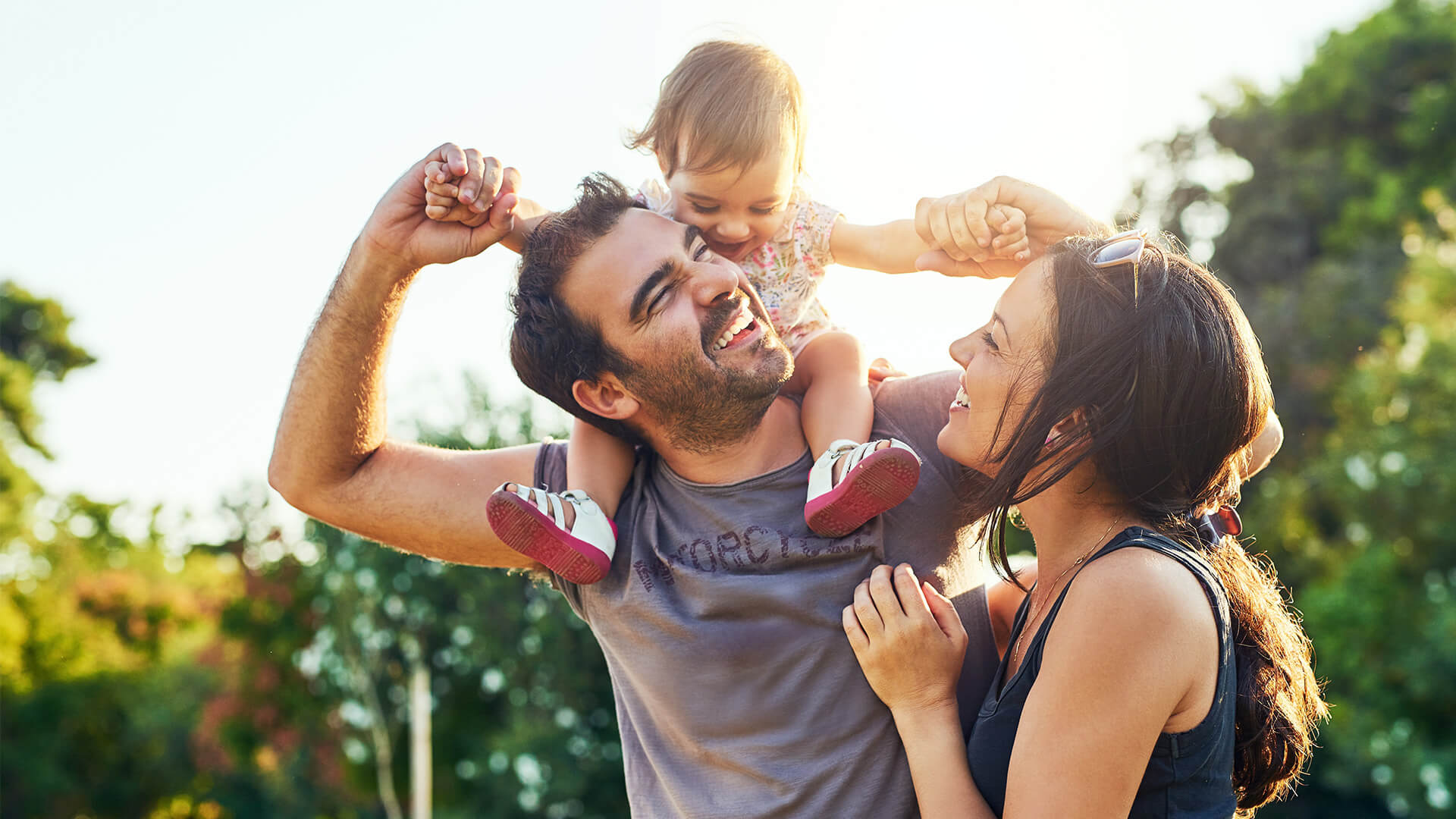 Three people outdoors enjoying time together in a sunlit park.
