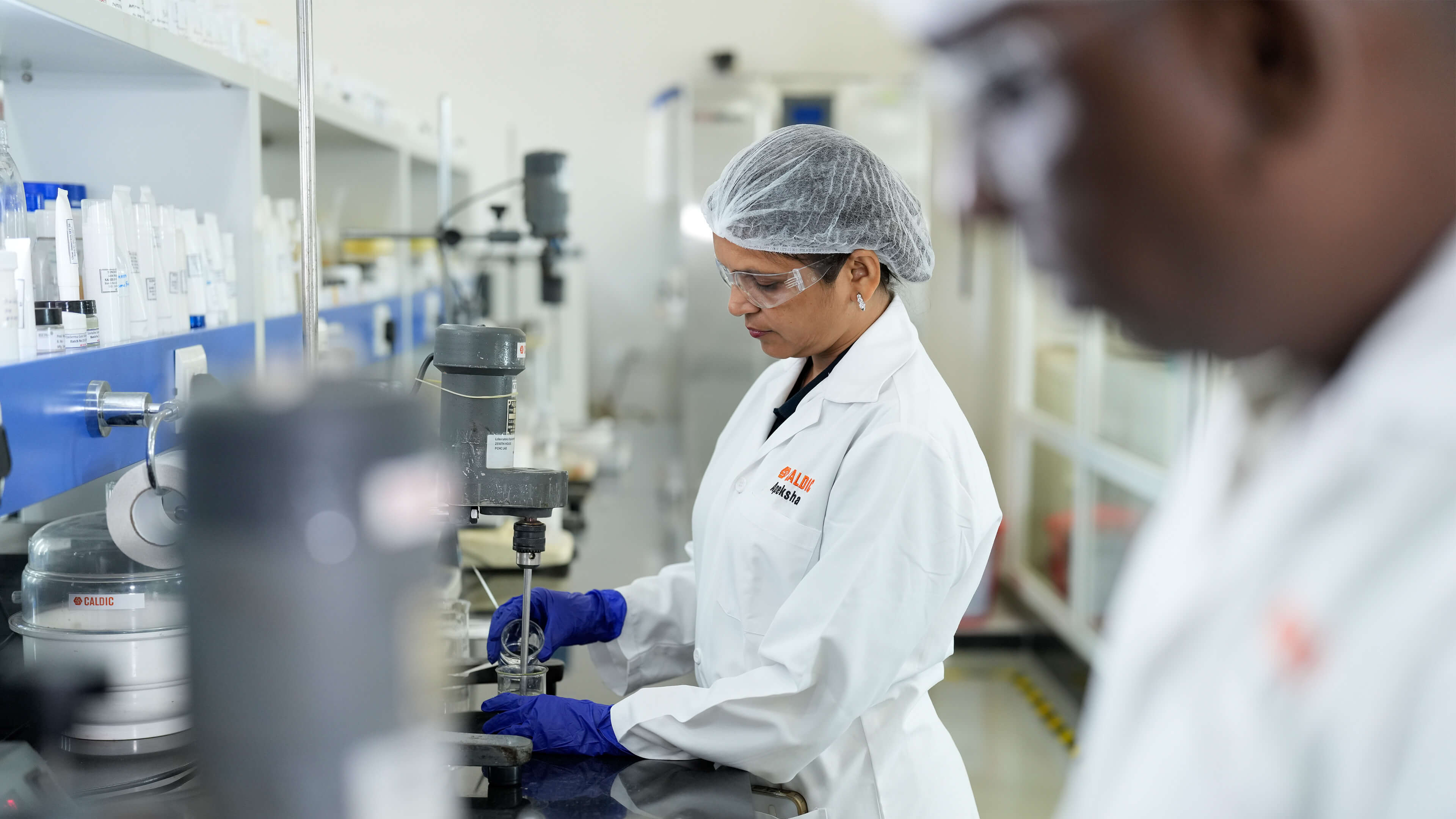 Laboratory technician operating mixing equipment while testing liquid formulation in controlled lab environment